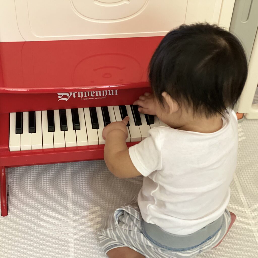 Jonathan playing red toy piano. AutumnLife Reflective Parenting