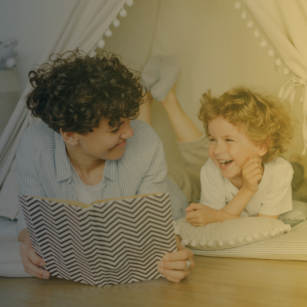 Mom and son reading book together under a play tent on the floor